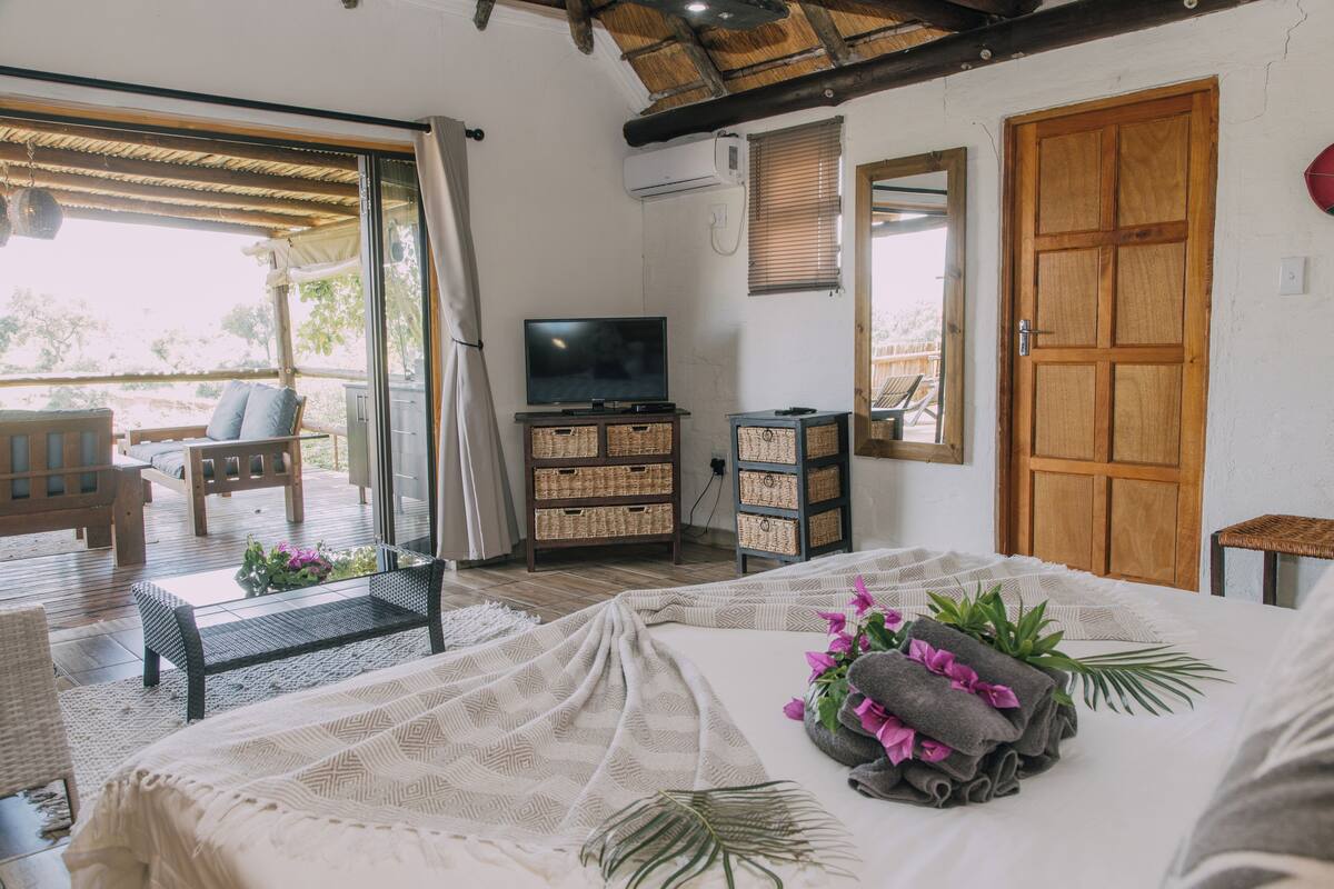A bedroom with a bed, a TV, wicker baskets, and a wooden door.