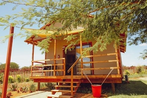 A wooden cabin with a porch, steps, and a red bucket. - Kruger View Chalets (Nkomazi)
