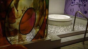 A bathroom with a large mirror, a bathtub, and a checkered floor.