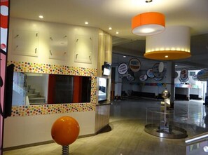 A modern interior with a staircase, a colorful wall design, and a large orange spherical object.