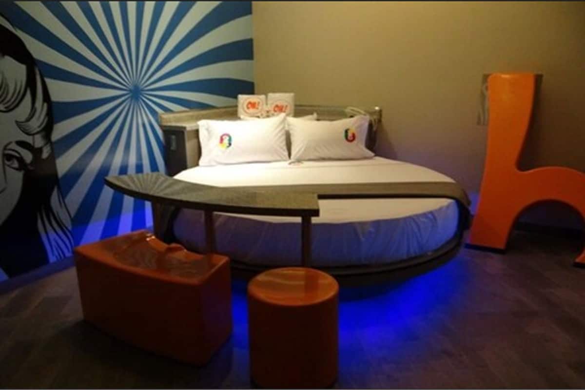 A bed with white bedding and a blue and white mural on the wall behind it.