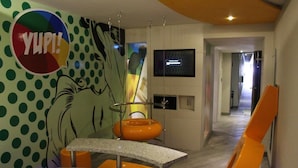A modern interior with a polka dot wall, a 'YUP!' sign, a kitchen area, and orange furniture.