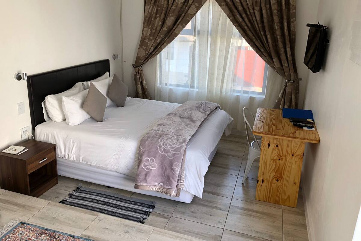 Une chambre à coucher comprenant un lit, une table de chevet et un bureau avec une chaise.