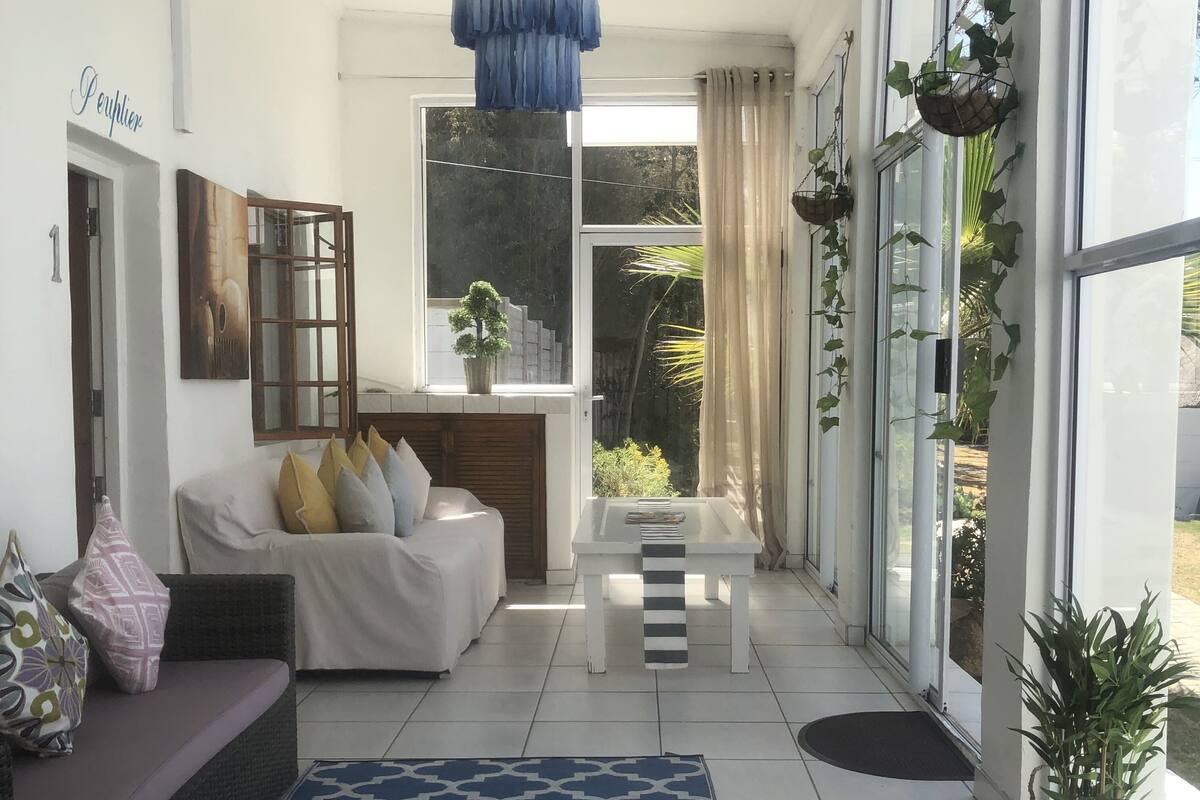 Un salon moderne avec un canapé blanc, un tapis à motifs et un luminaire suspendu.