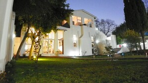 A modern building with a flat roof, large windows, and a well-lit entrance. - Muco Guest House (Sandton)
