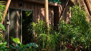 A wooden building with a metal roof, surrounded by lush greenery and a large tree. - Green Sanctuary Hotel (Nosara)