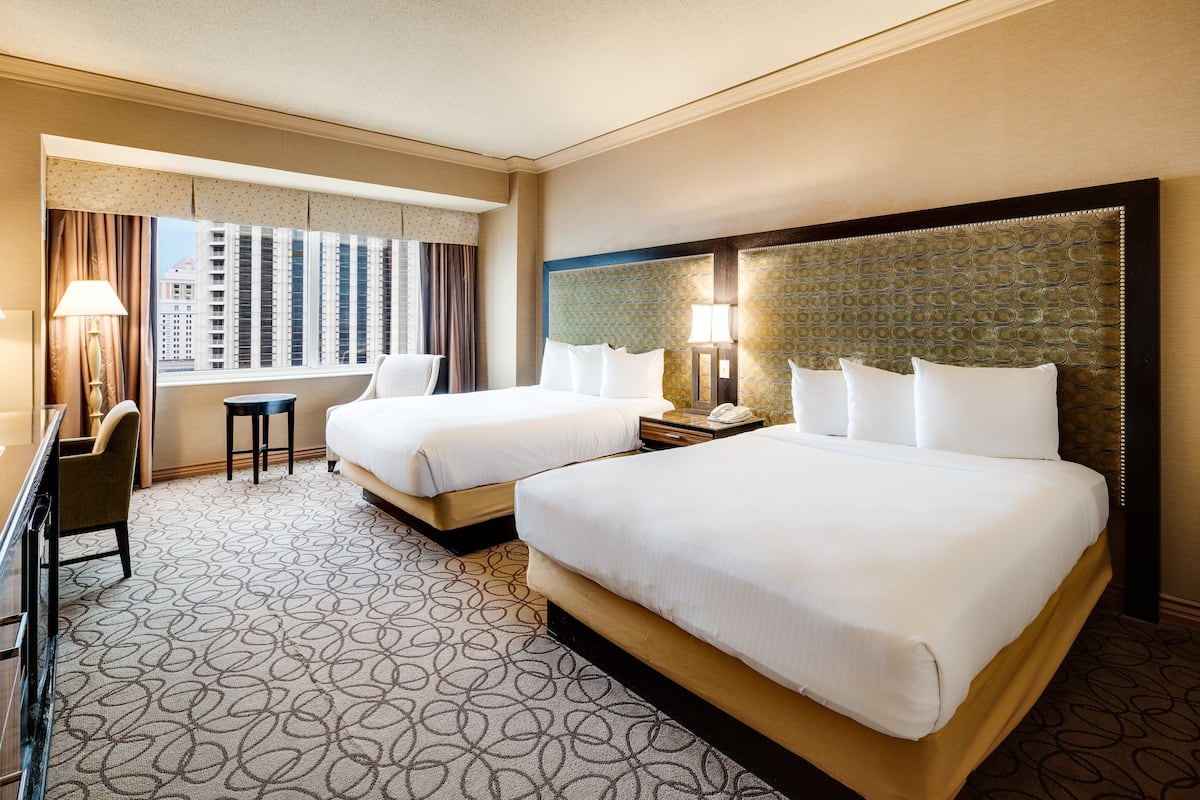 A hotel room with two beds, a desk, and a chair.