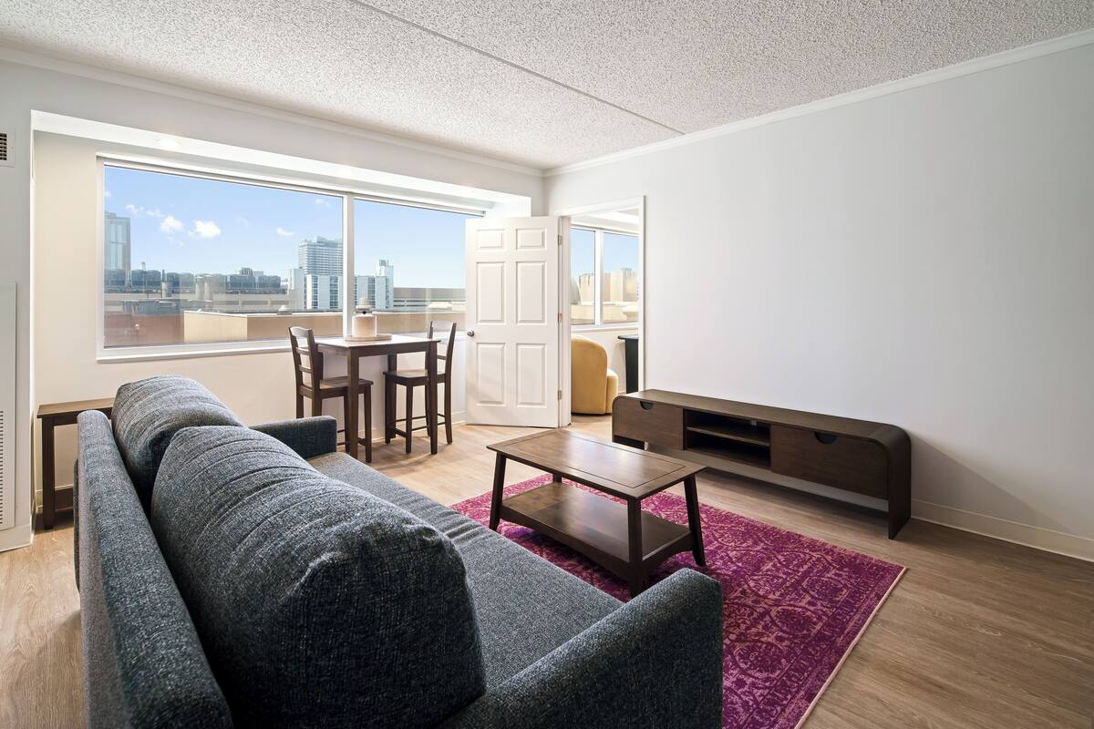 A modern living room with a sofa, coffee table, and dining area.