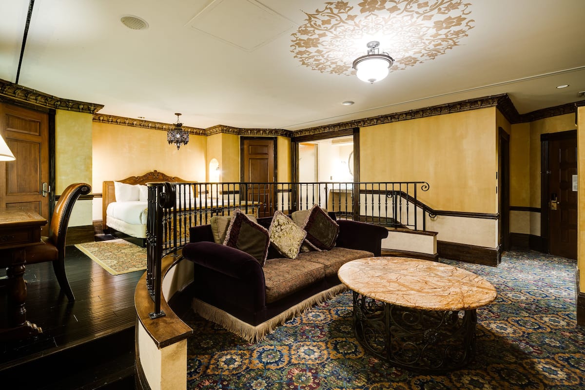 A room with a dark-colored sofa, a round table, and a patterned carpet.
