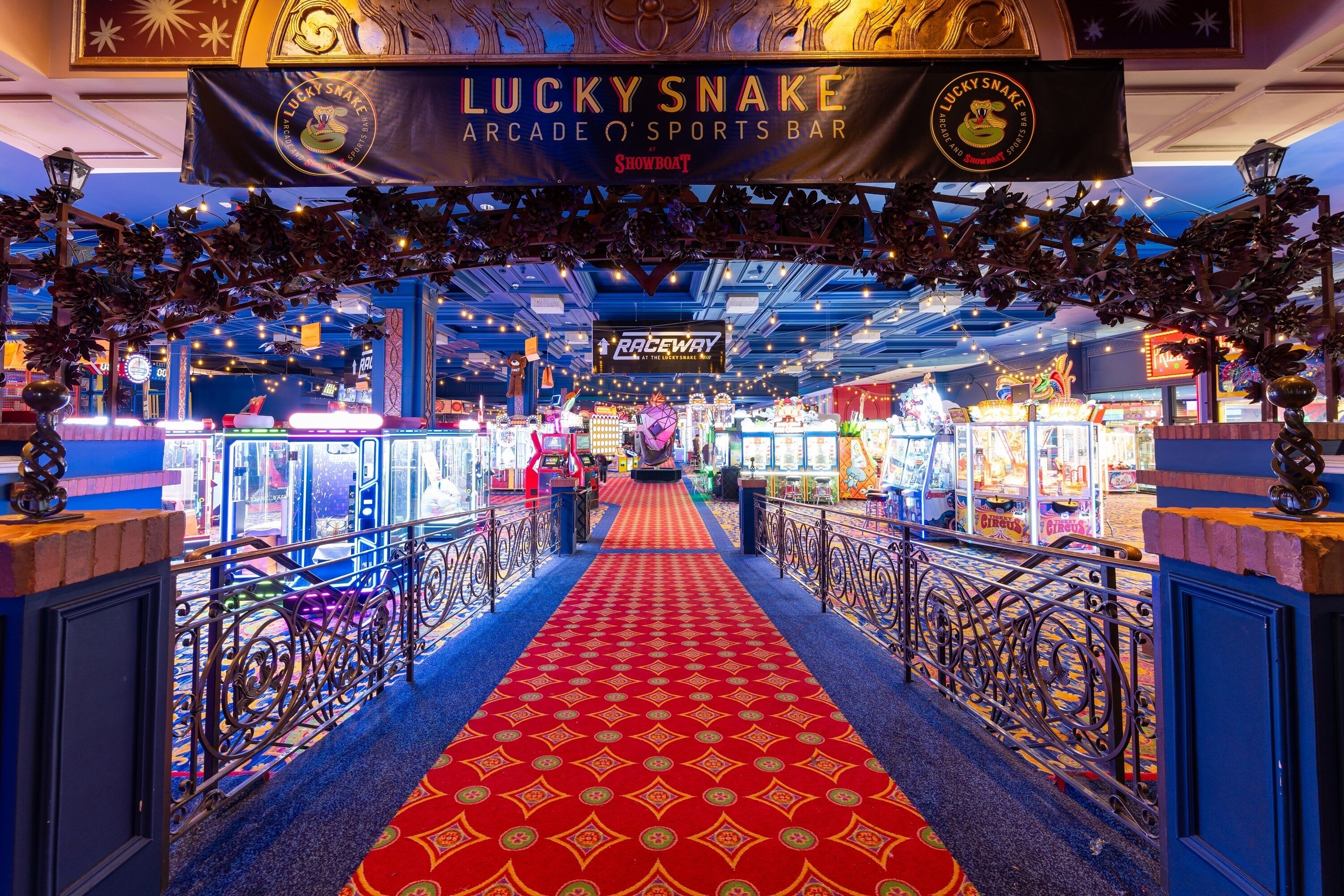 An indoor arcade area with a red carpet, arcade machines, and a sign for 'Lucky Snake Arcade & Sports Bar'.