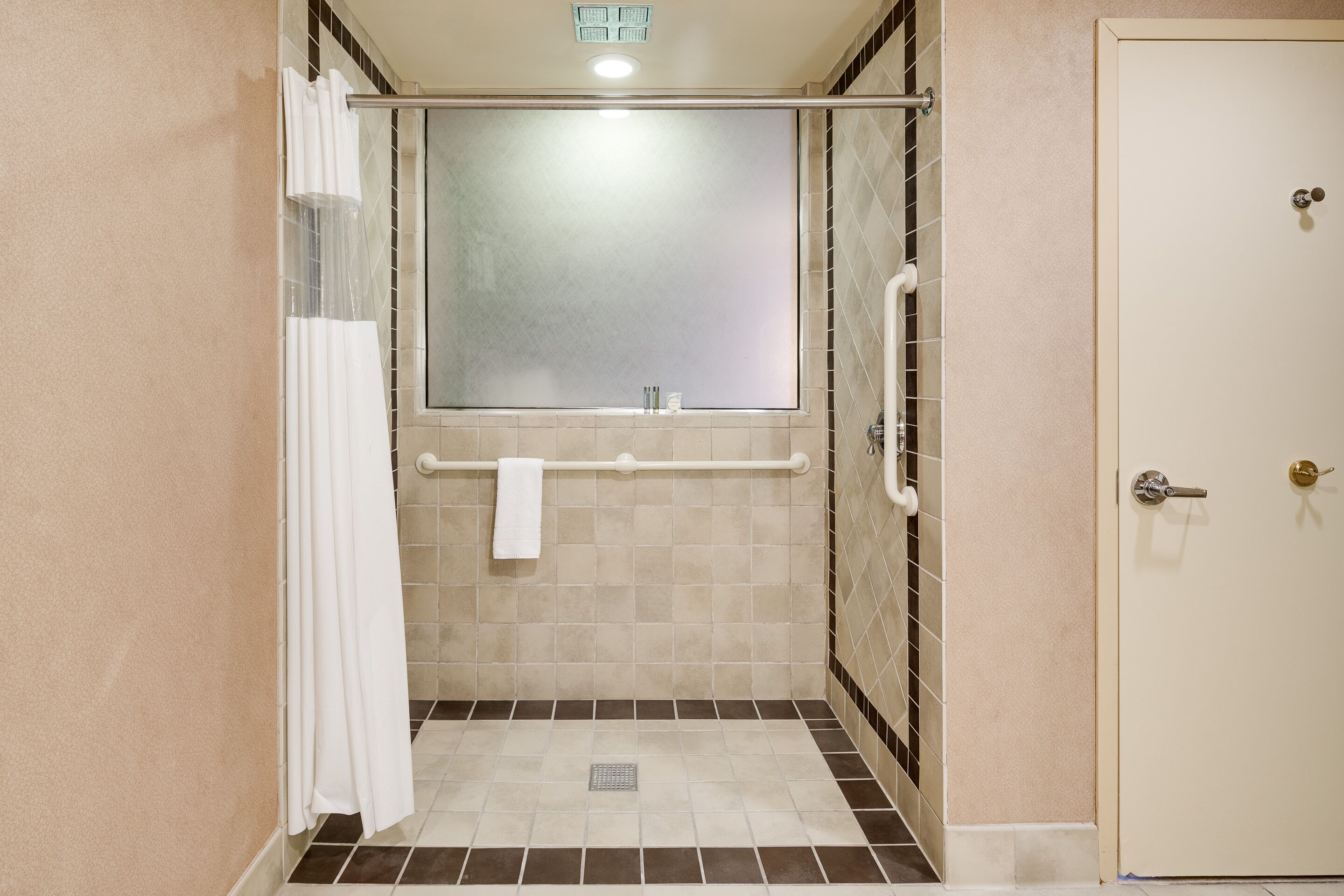 A small, enclosed shower area with a glass door, a towel rack, and a tiled floor.