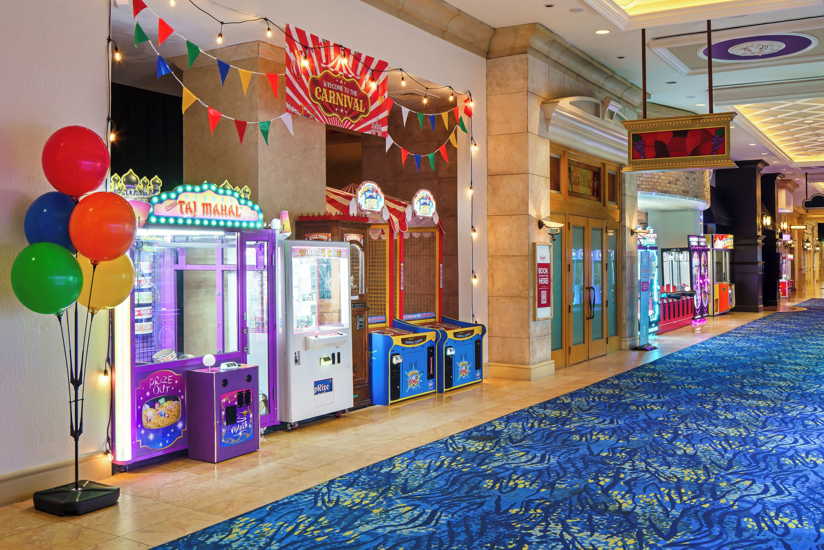 A corridor with arcade games, a blue carpet, and a 'Carnival' sign.