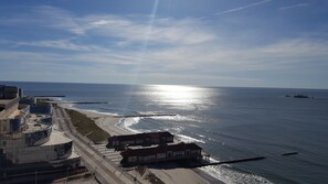 Une vue sur la côte, avec une plage, une jetée et un bâtiment doté d’un toit incurvé.