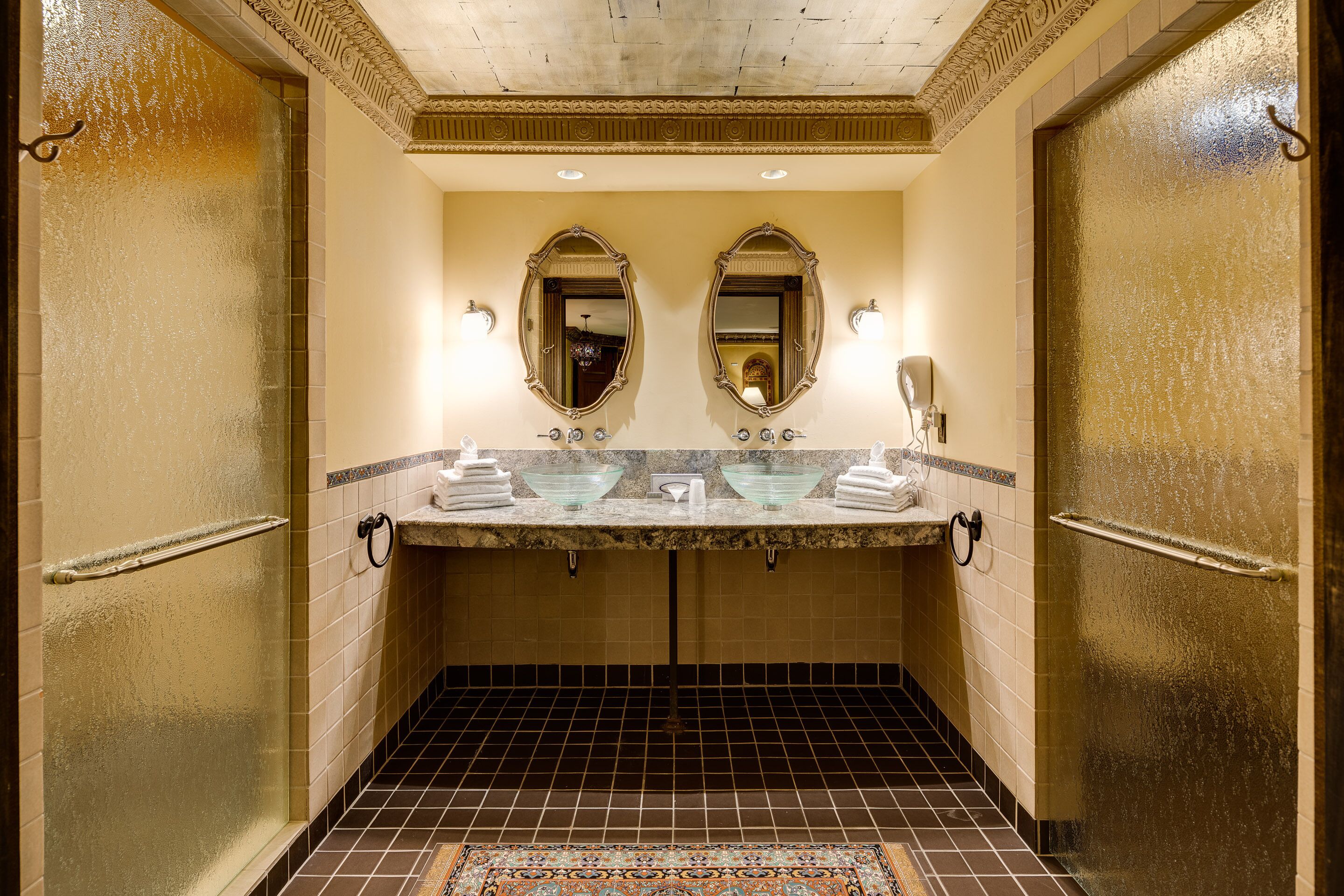 A bathroom with two sinks, mirrors, and a tiled floor.