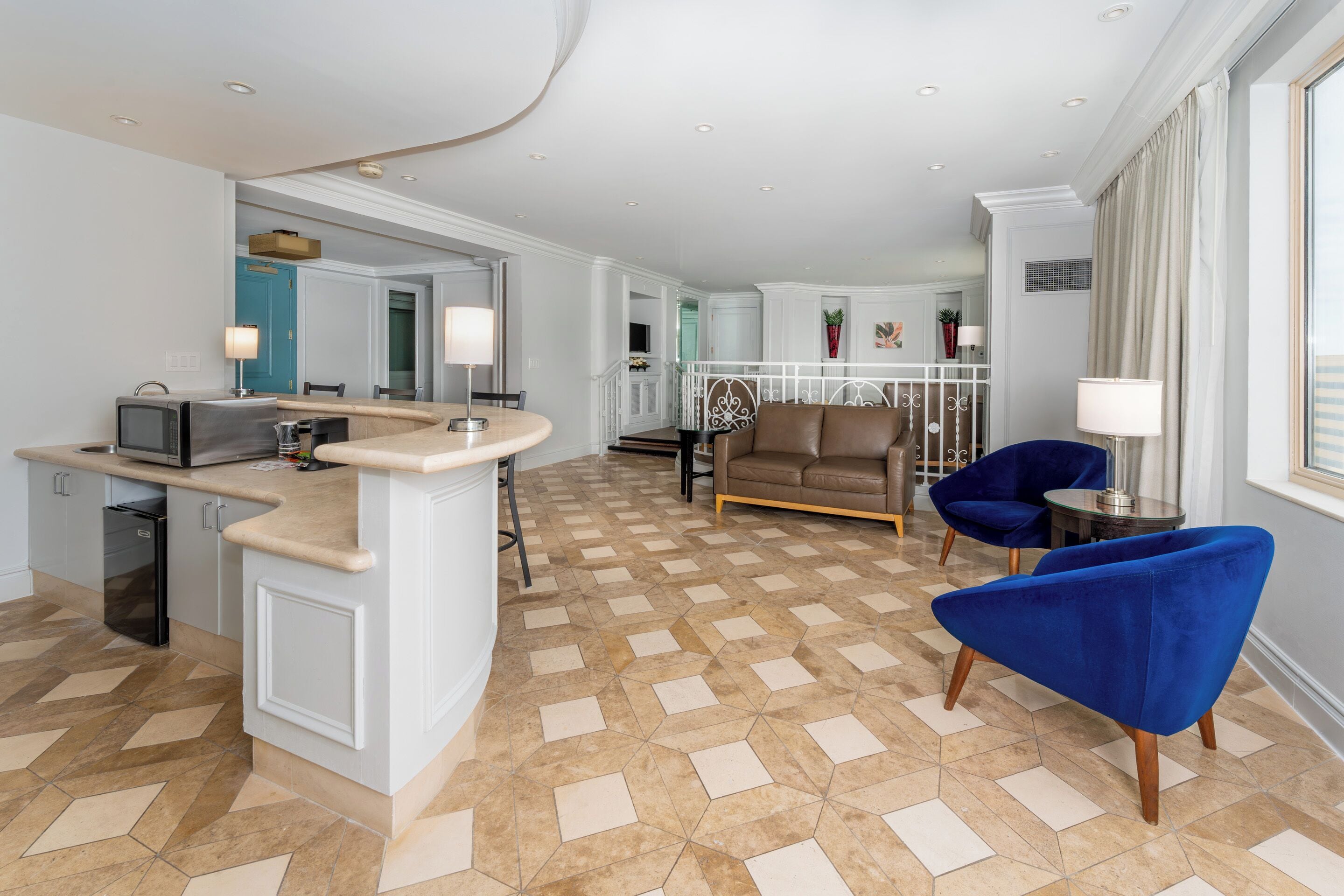 Een moderne woonkamer met een keukeneiland, zitplaatsen en uitzicht op de omgeving.