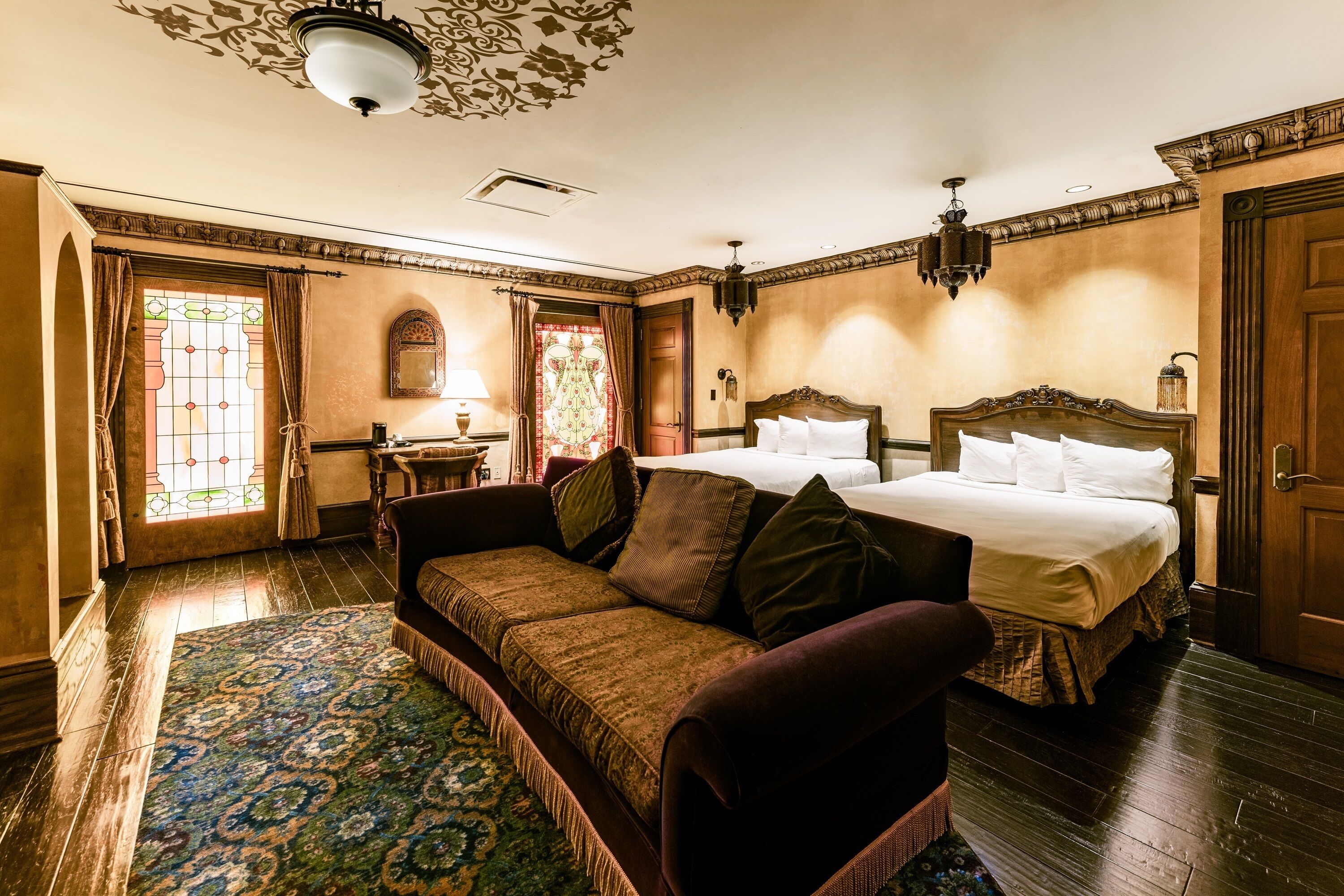 Ein traditionell eingerichtetes Schlafzimmer mit einem großen Bett, einer Couch, einem kleinen Tisch und einem Spiegel.