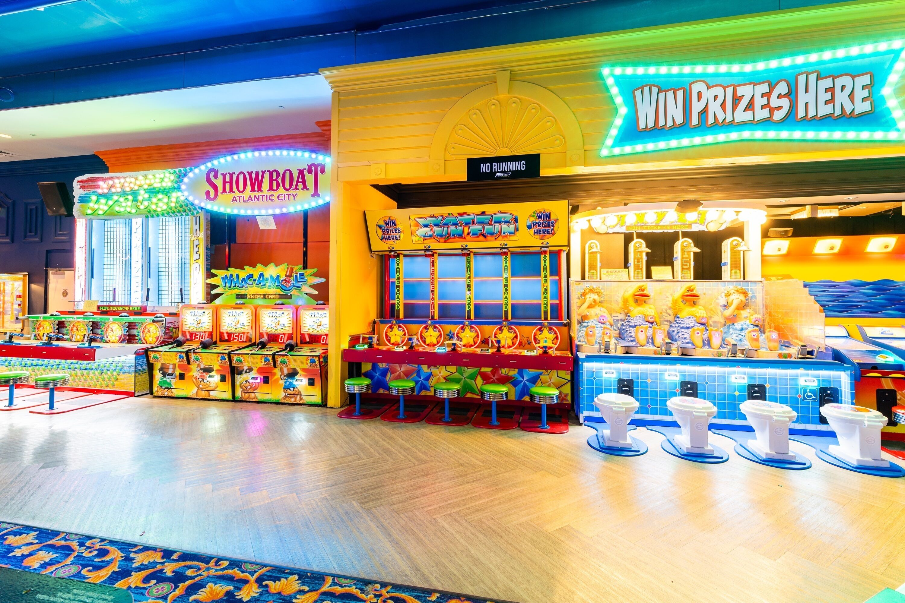 Un salón recreativo con varios juegos y un letrero que dice 'Gana Premios Aquí'.
