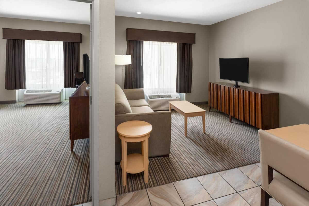 Una habitación de hotel con un sofá, una mesita redonda, un televisor y un armario.