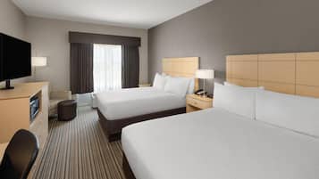 Een hotelkamer met twee bedden, een televisie, een bureau en een stoel.