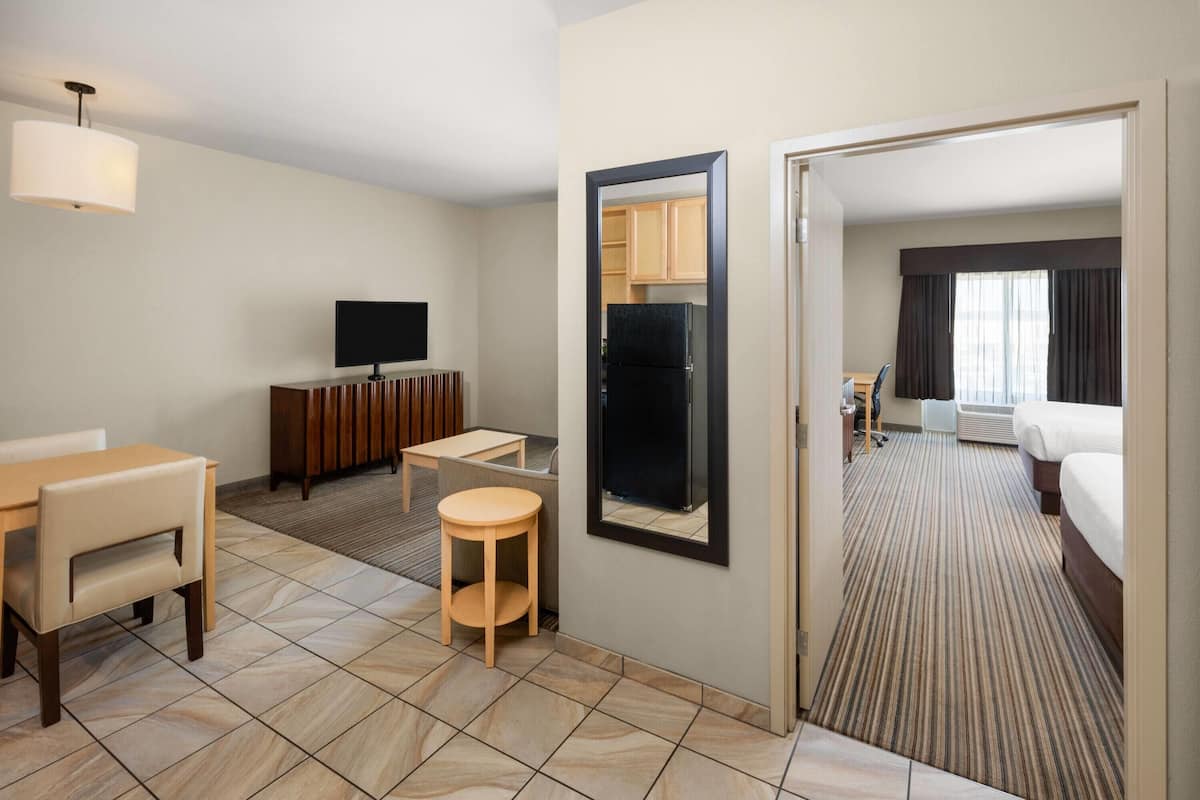 Una habitación de hotel con cama, escritorio, silla, televisor y refrigerador.
