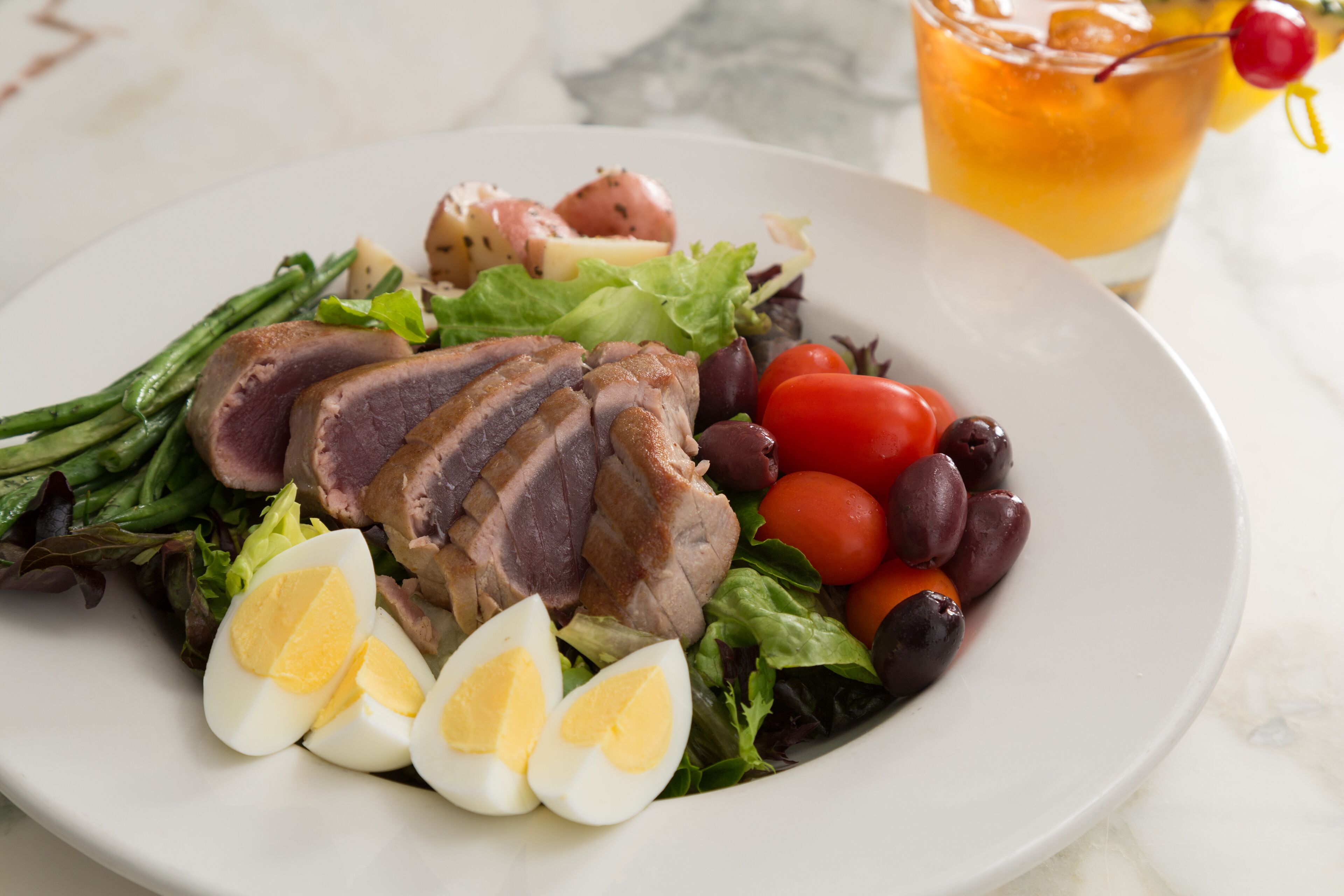 Ein Teller Essen mit geschnittenem Fleisch, gekochten Eiern und Gemüse.