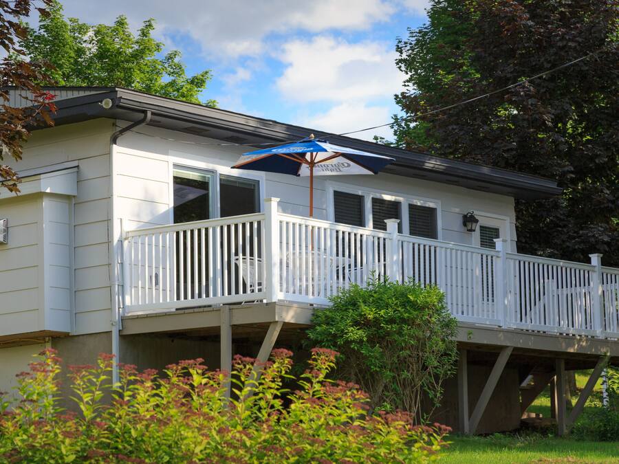 A two-story house with a balcony, a covered patio area, and a small garden.