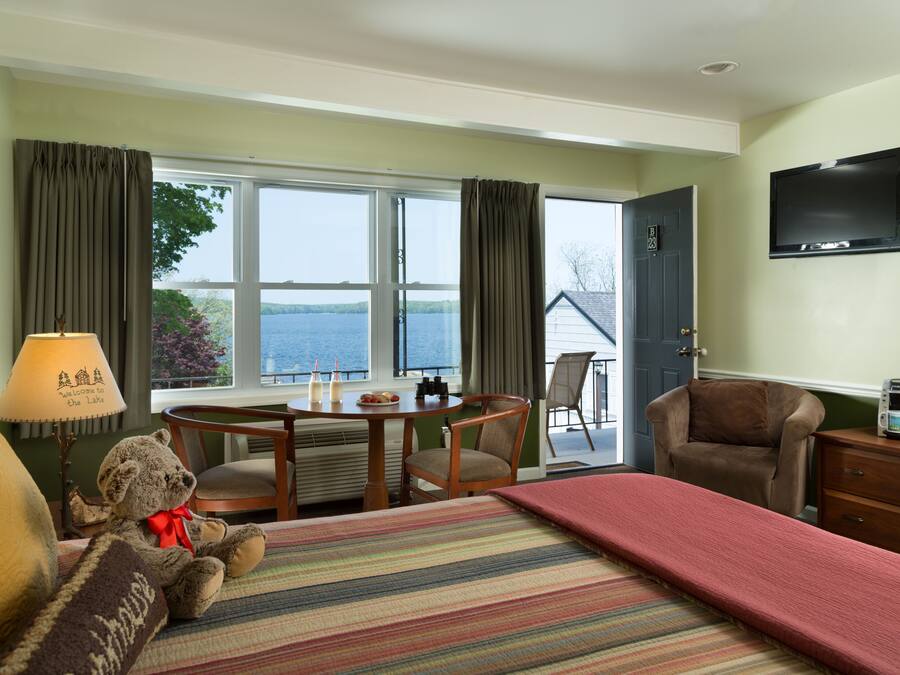 A hotel room with a bed, a desk, a chair, a television, and a view of the sea.