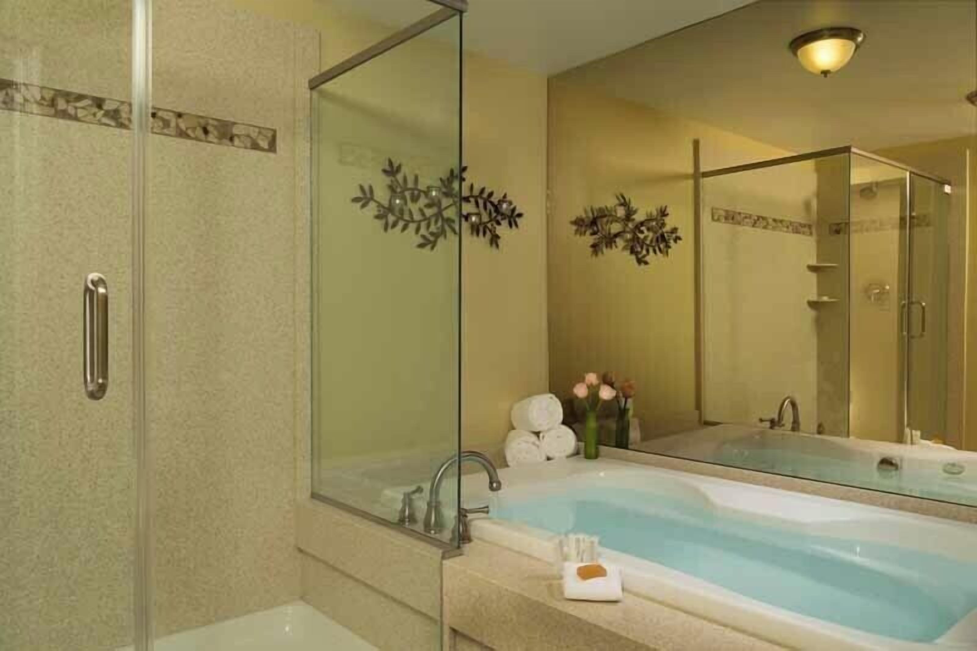 Une salle de bain moderne avec une douche à parois de verre, une grande baignoire et un meuble-lavabo avec un miroir.