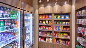 Una tienda de comestibles con bebidas refrigeradas, pasillos de bocadillos y productos envasados.