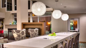 Un comedor moderno con una mesa larga, sillas estampadas e iluminacion esférica decorativa.