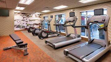 A fitness center with treadmills, ellipticals, and a bench.