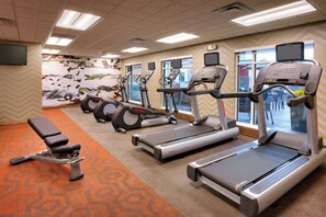 A fitness center with treadmills, ellipticals, and a bench.