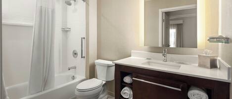 A modern bathroom with a bathtub, toilet, and vanity with a mirror.