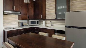 A modern kitchen with dark wood cabinets, a stainless steel refrigerator, a microwave, and a built-in oven.
