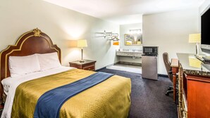 Una habitación de hotel con cama, escritorio, televisor y baño.
