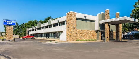 A modern building with a sign for Rodeway Inn, featuring a parking lot and a red vehicle.