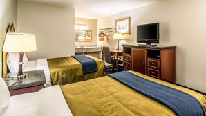 Una habitación de hotel con dos camas, un escritorio, un televisor y un espejo.