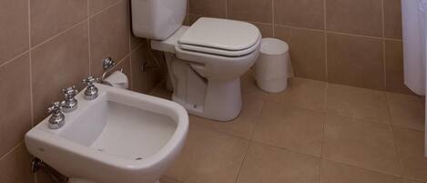 Un baño con inodoro, bidé y toallero.