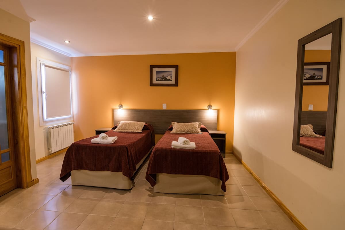 A hotel room with two beds, a large mirror, and a picture on the wall.