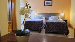 A hotel room with two beds, a potted orchid, and a framed picture on the wall. - Vertical Lodge (El Chalten)
