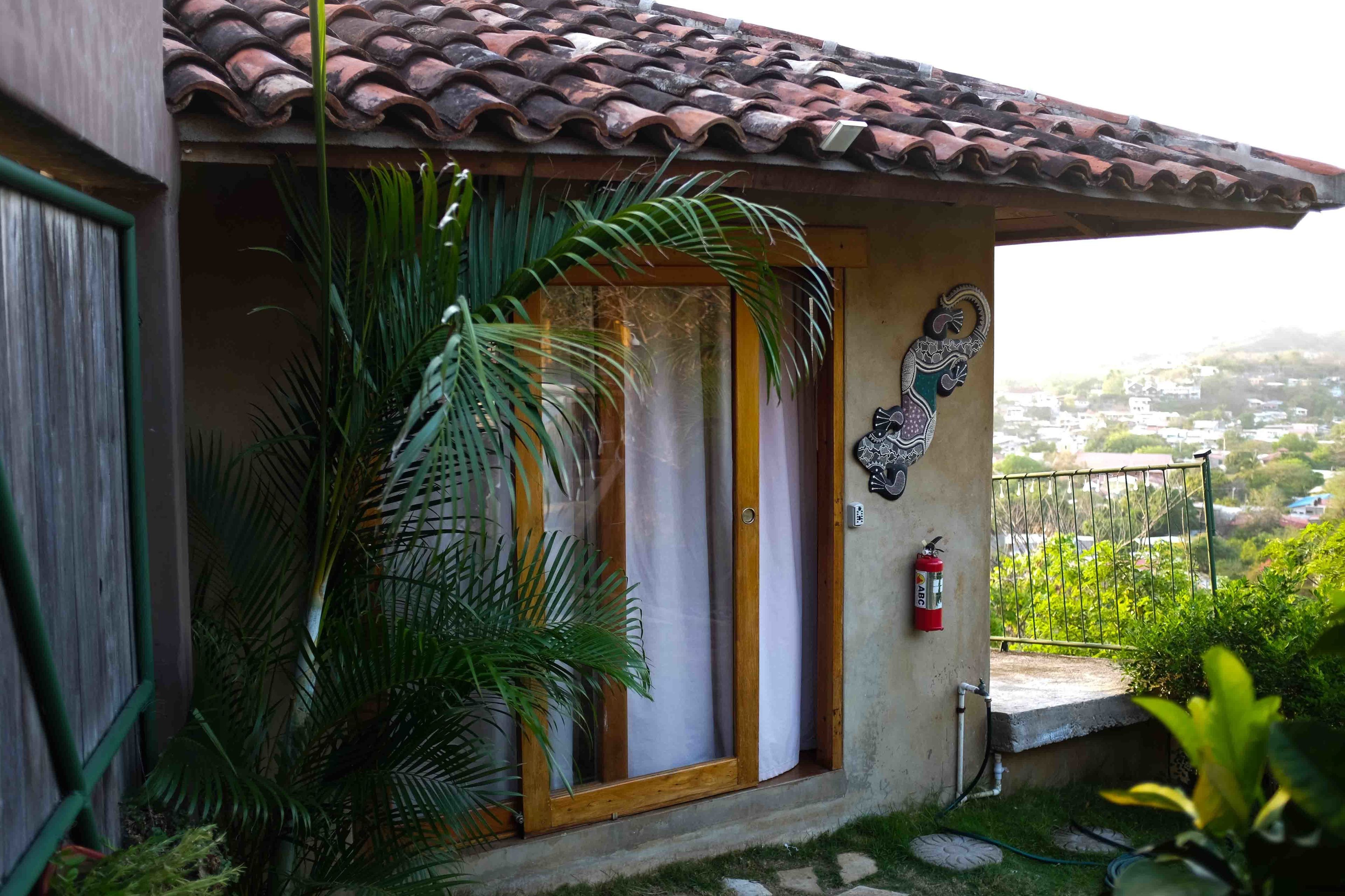 A house with a tiled roof, a wooden door, and a fire extinguisher mounted on the wall.