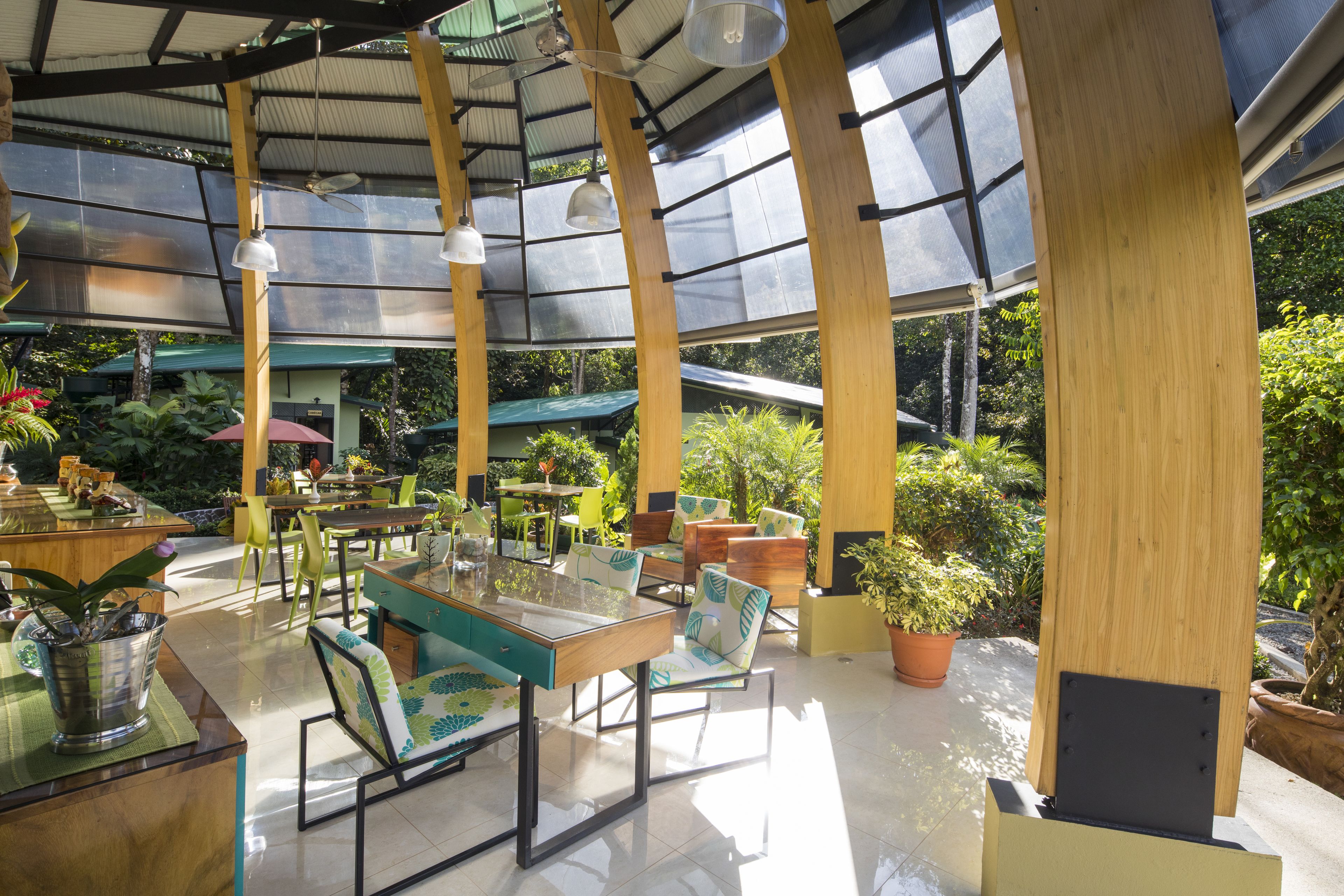 Ein Wintergarten mit Tischen und Stühlen, umgeben von Topfpflanzen und einer Glaskuppel.