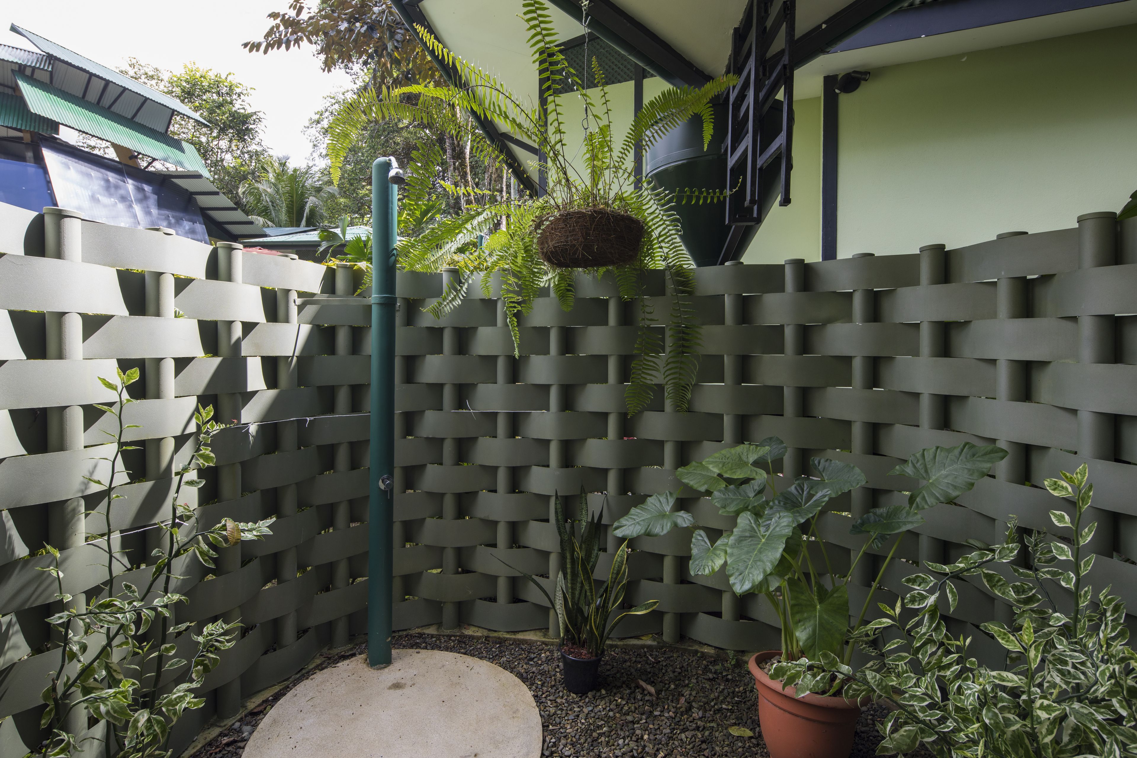Un jardín con cerramiento de madera, plantas en macetas y un nido colgante.