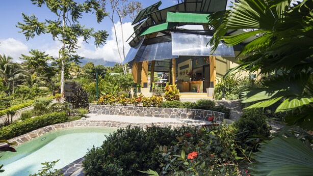 Ein Resort mit Pool, üppiger Vegetation und einem modernen Gebäude mit Gründach.