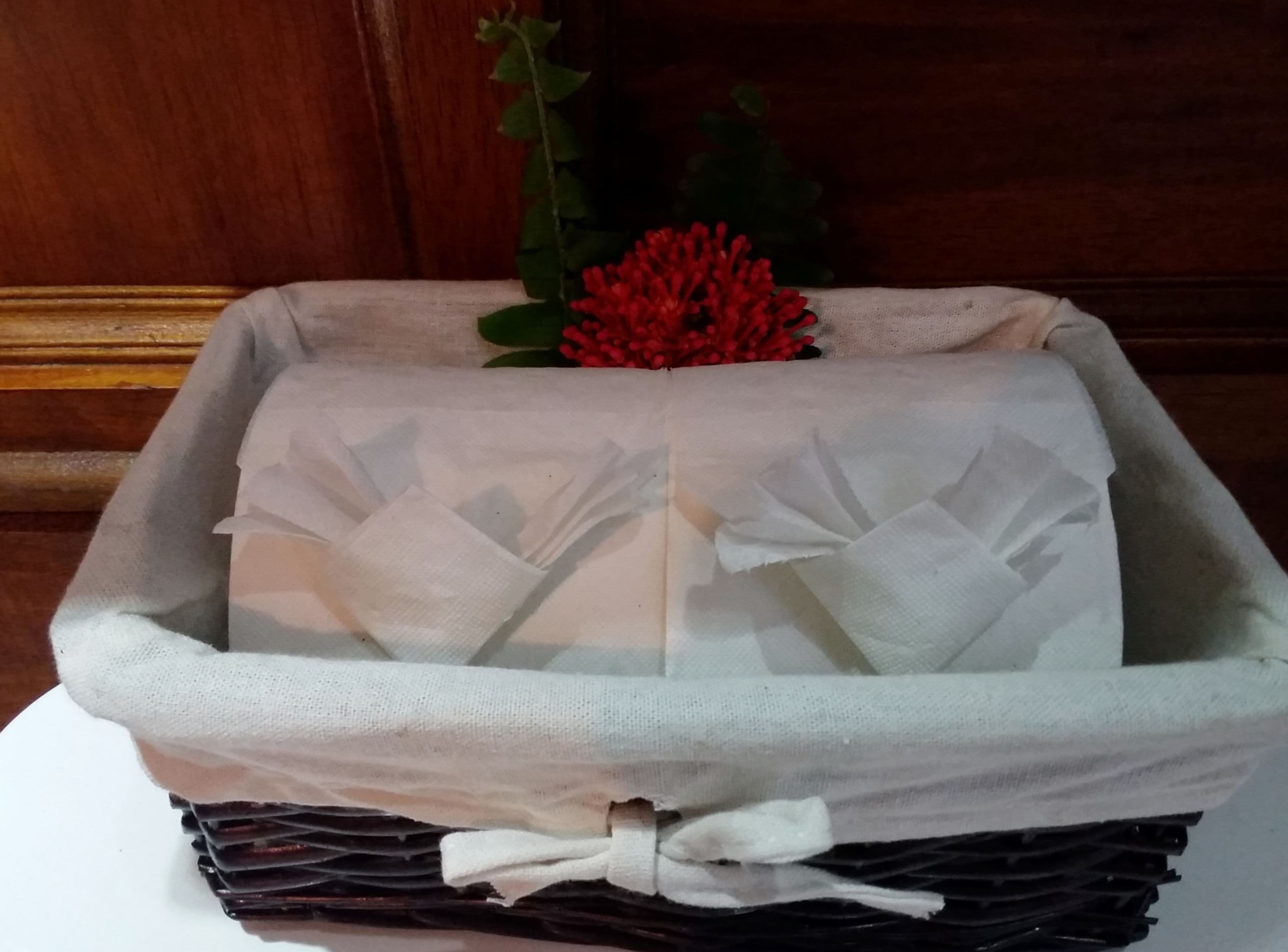 A neatly folded white cloth with a bow, placed on a dark surface.