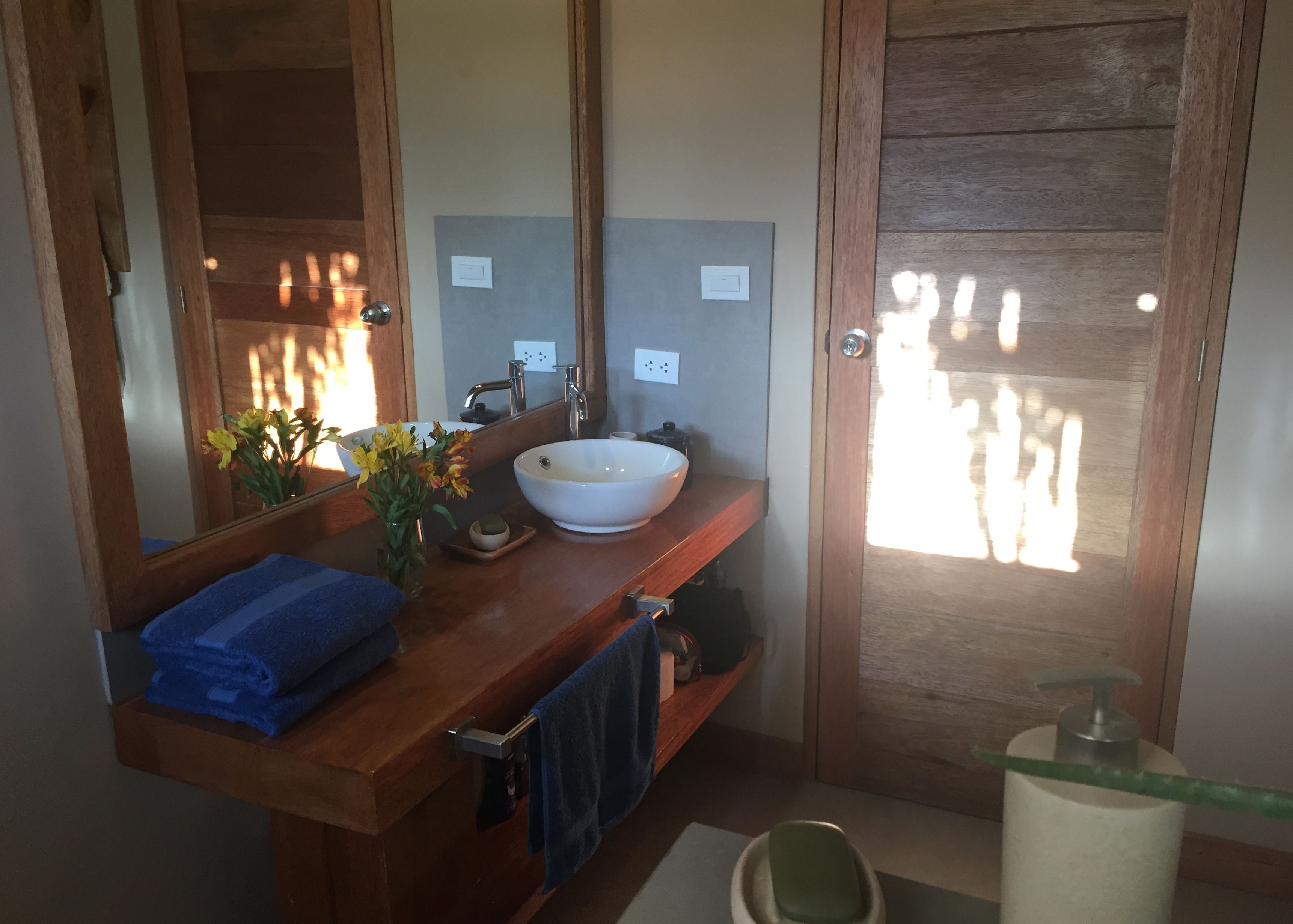 A bathroom with a wooden vanity, a white sink, a mirror, and a towel rack.