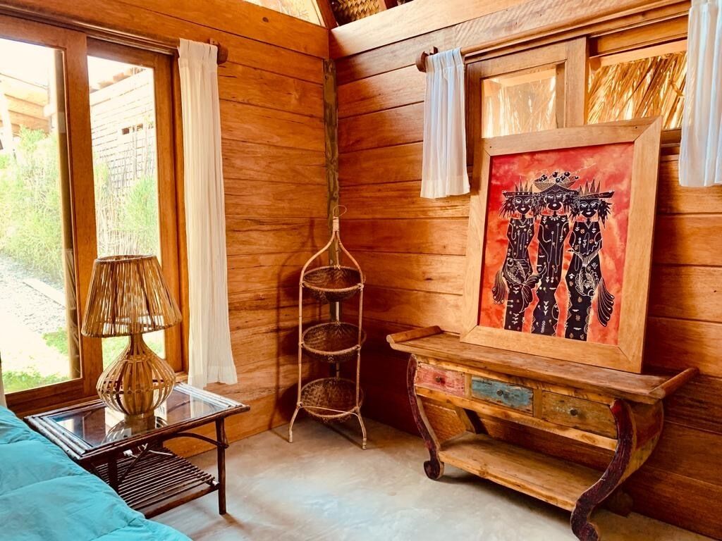 Una habitación de madera con una cama, una lámpara, una estantería y un cuadro en la pared.