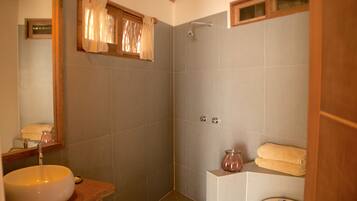 Un baño con un lavamanos amplio, ducha y retrete.
