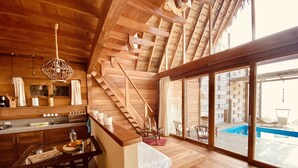 Una cocina moderna con detalles de madera, un comedor y un amplio ventanal corredera que da a una zona de piscina.