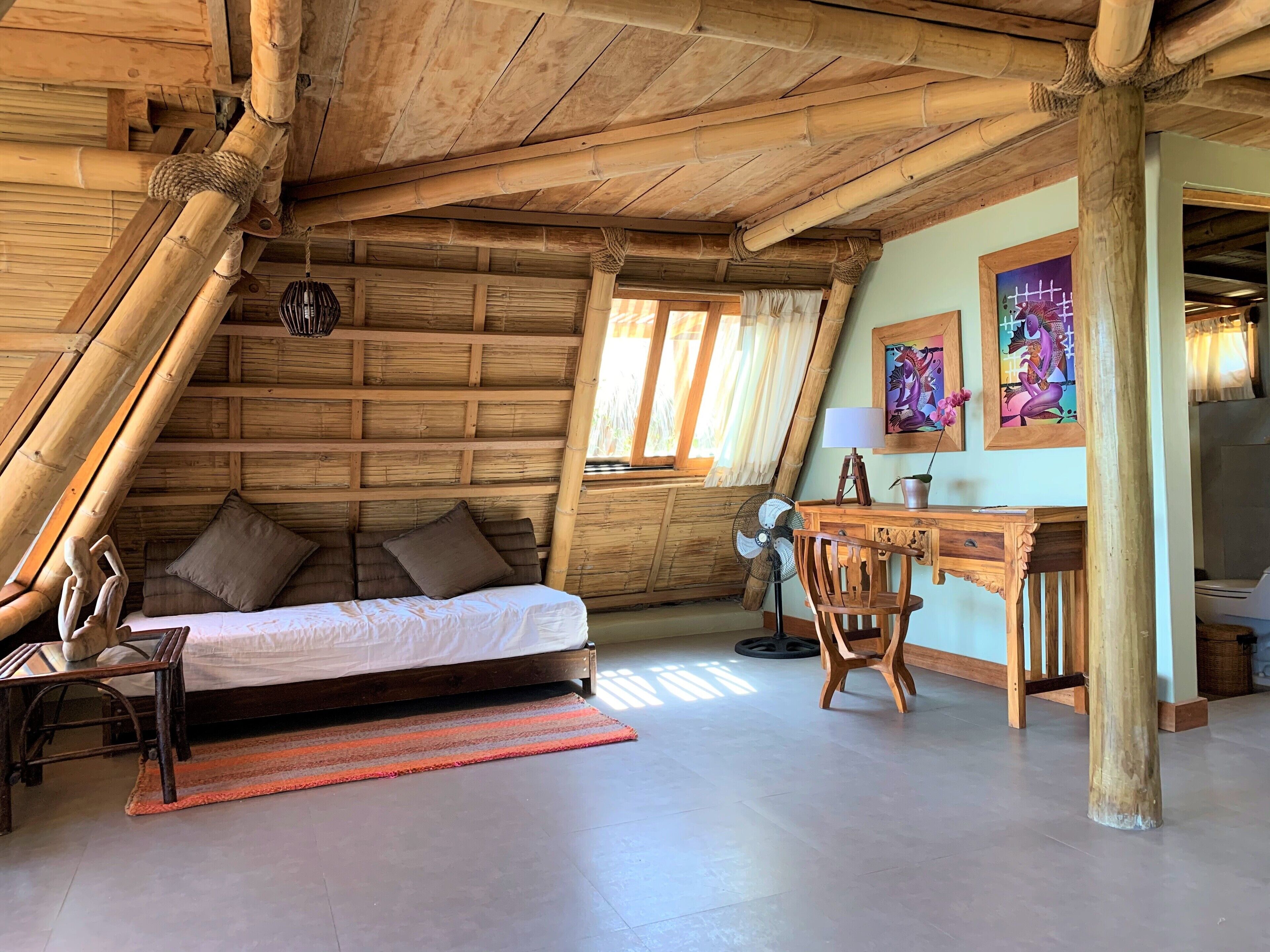 A cozy room with a bed, a desk, and a chair. The room has wooden walls and a sloped ceiling.